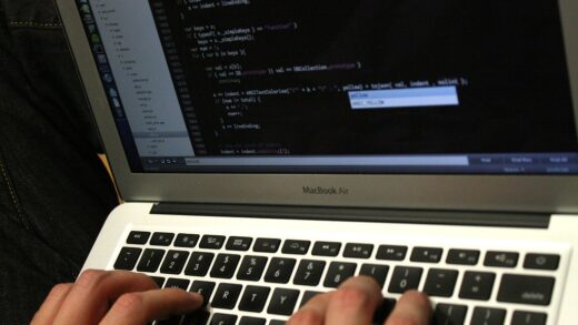 Manos escribiendo código en el teclado de un portátil